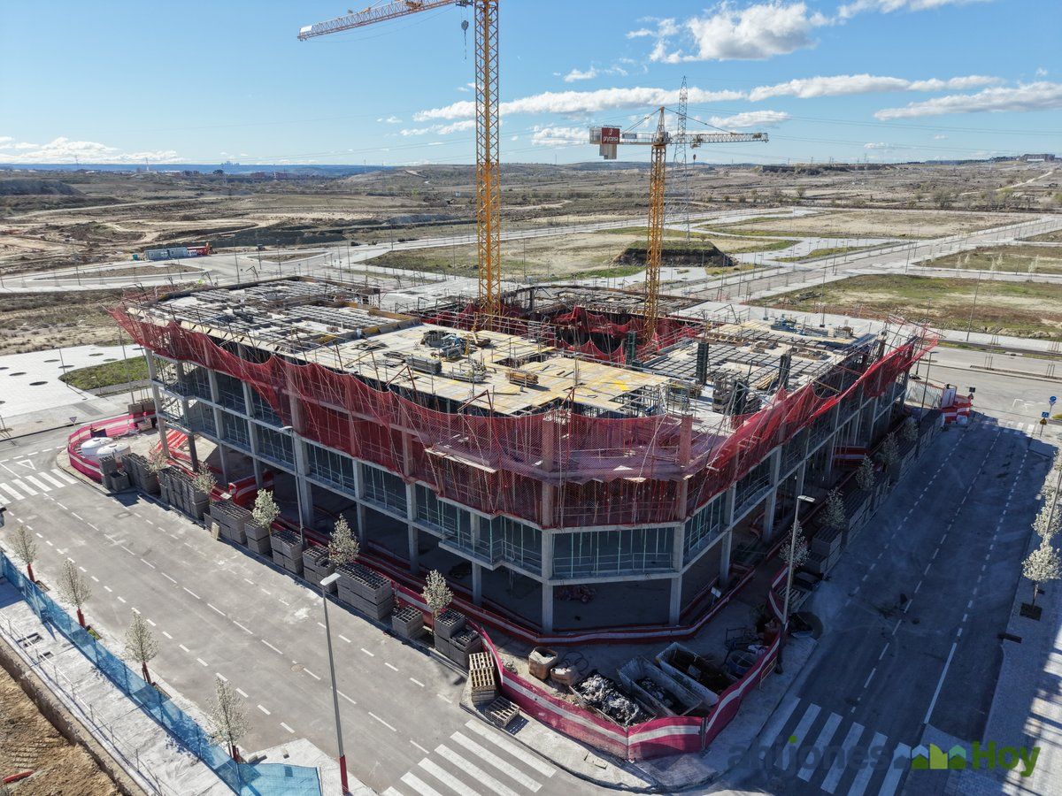 Vista aérea de edificio en construcción con estructura avanzada y redes de seguridad