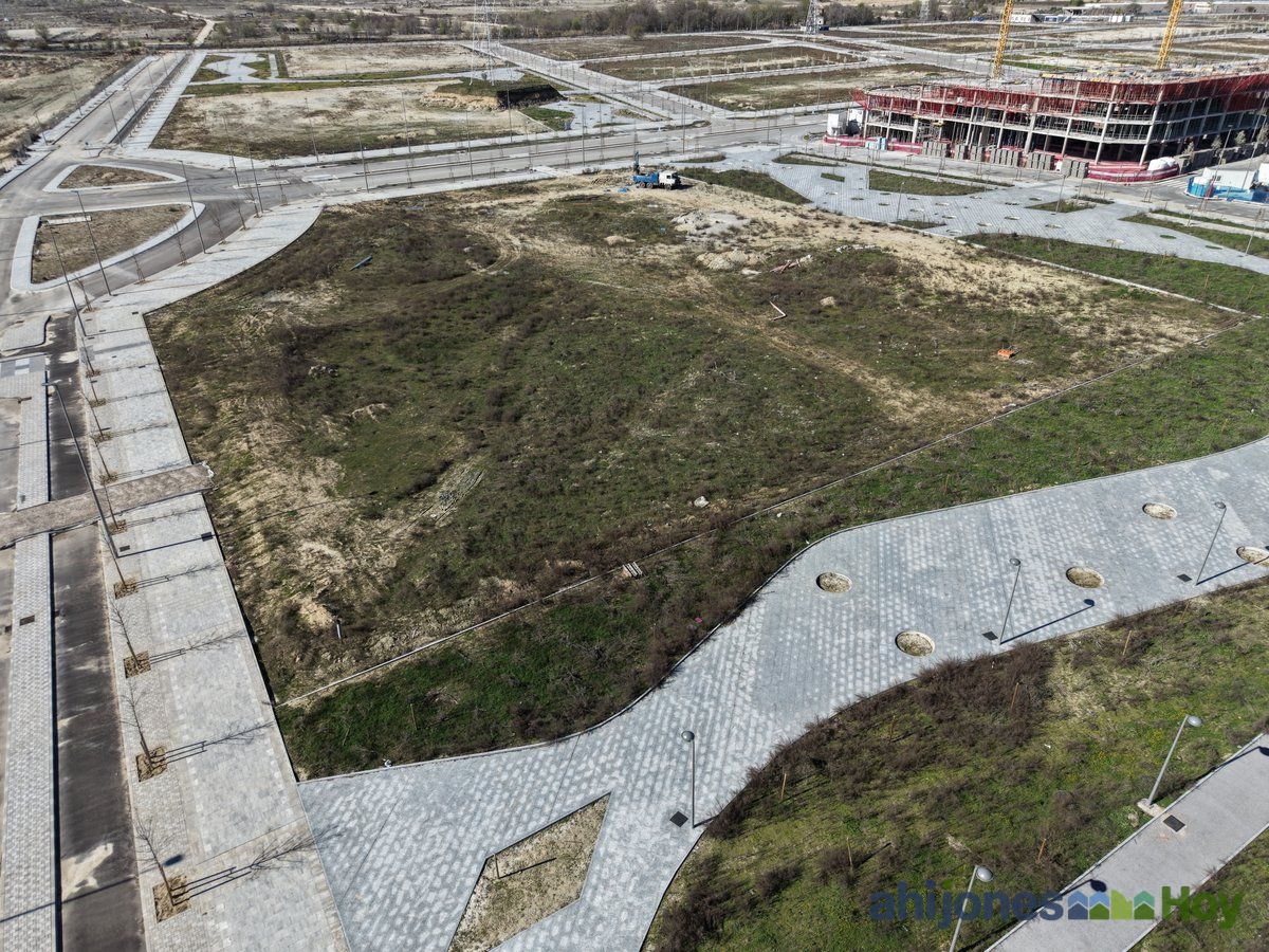 Parque junto a edificio en construcción con senderos y zonas ajardinadas